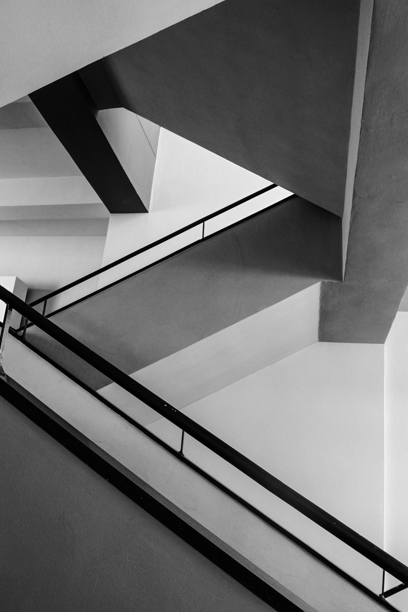 eine klassische Bauhaustreppe in dem Bauhausmuseum Dessau in Schwarz-Weiß mit den schlichten und schönen Treppenwangen.